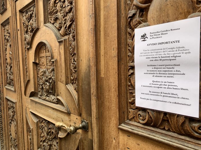 Avviso coronavirus all'esterno della collegiata di San Vittore Mauro a Poschiavo